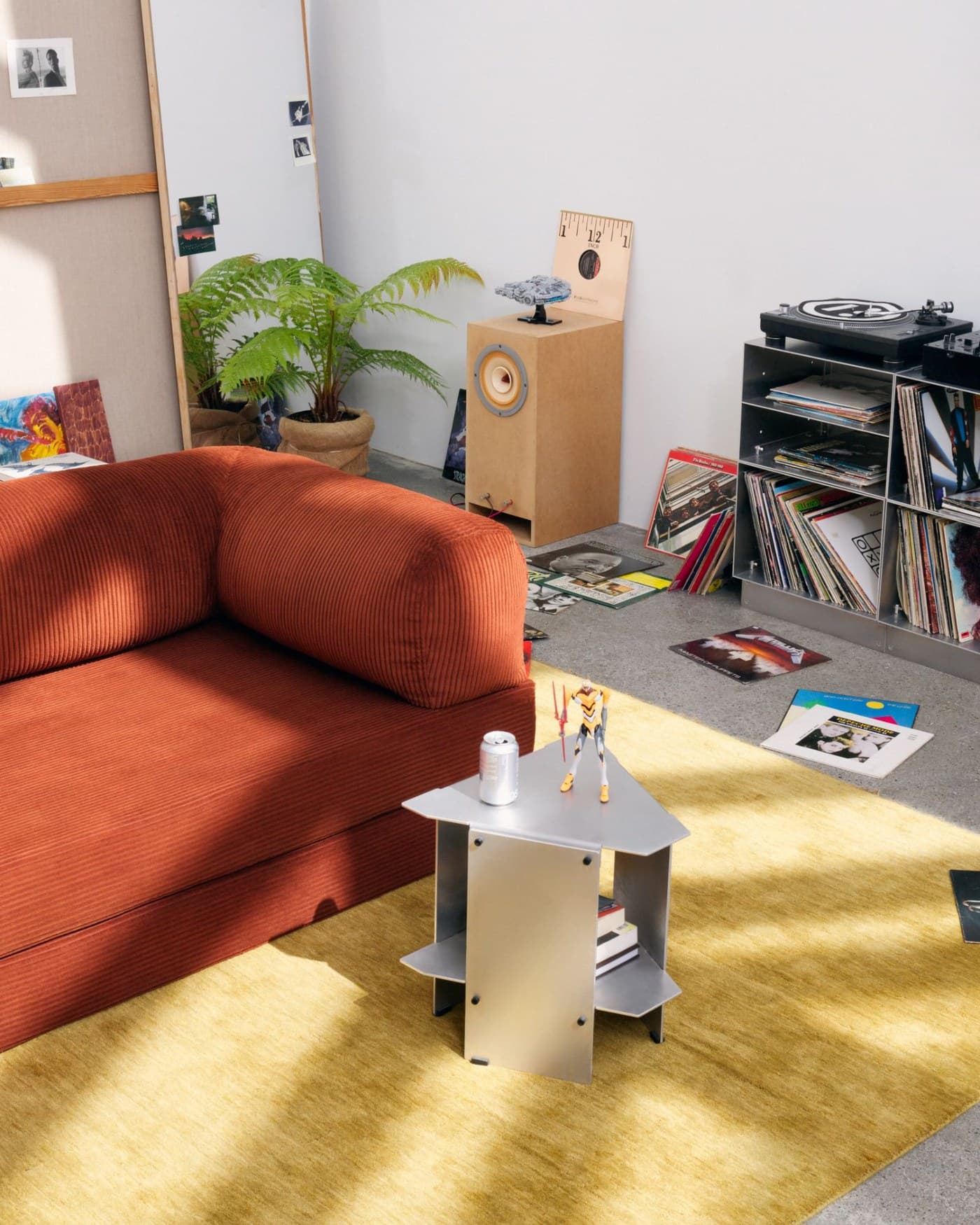 An OMHU modular corduroy sofa in rust, in a room with a record collection, turntable and a yellow rug